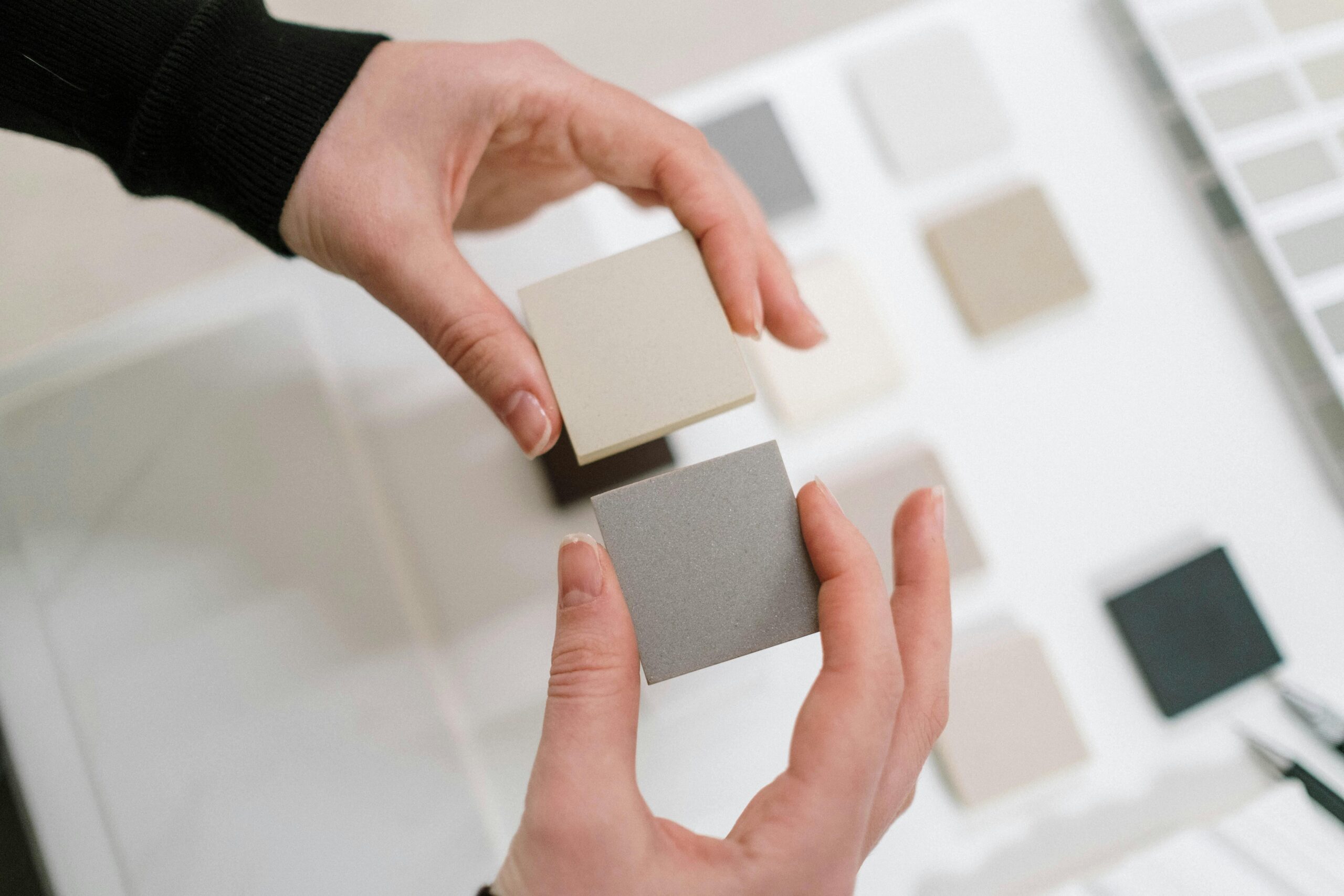 Hands holding neutral color swatches for interior design selection.
