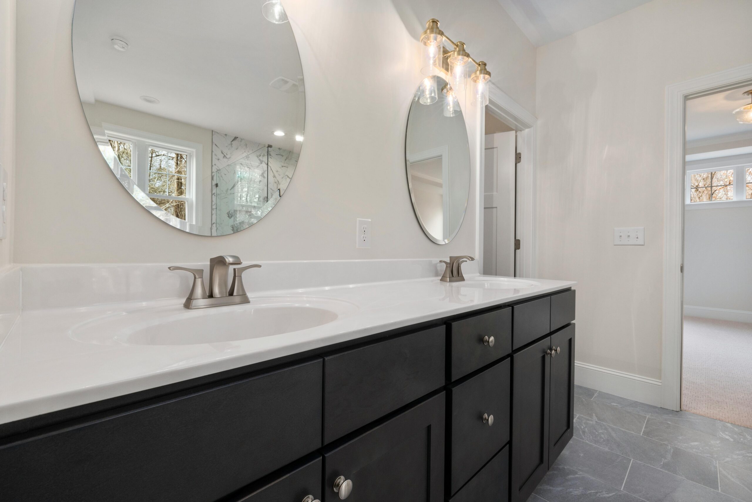 Elegant bathroom interior featuring round mirrors and contemporary vanity.