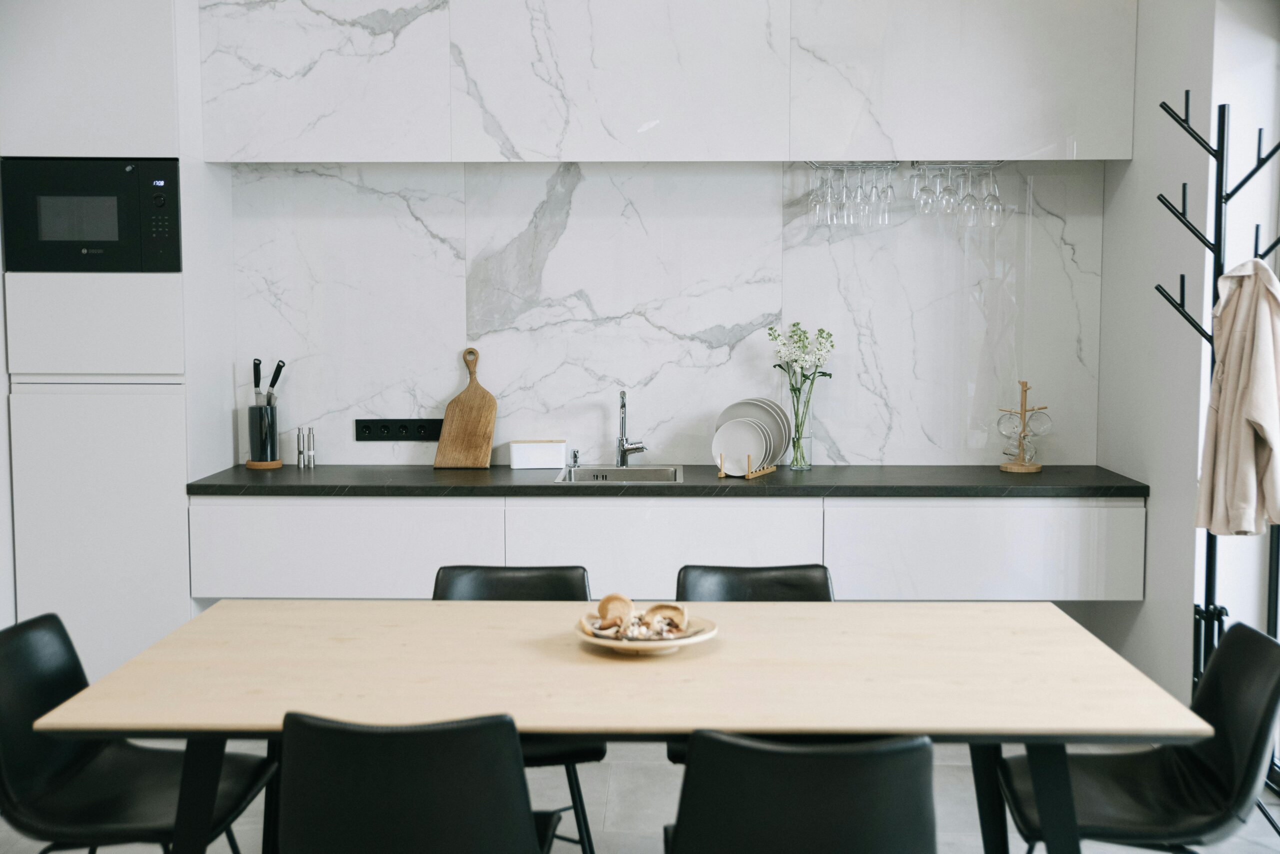 Sleek Japandi-style kitchen featuring marbled walls, dining setup, and minimalistic decor.