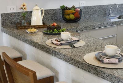 A cozy kitchen counter setup with two places set for breakfast, featuring cups and a cake.