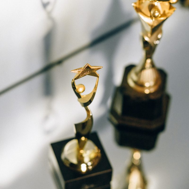 Close-up of shiny golden star trophies reflecting on a glass surface, perfect for award-themed concepts.